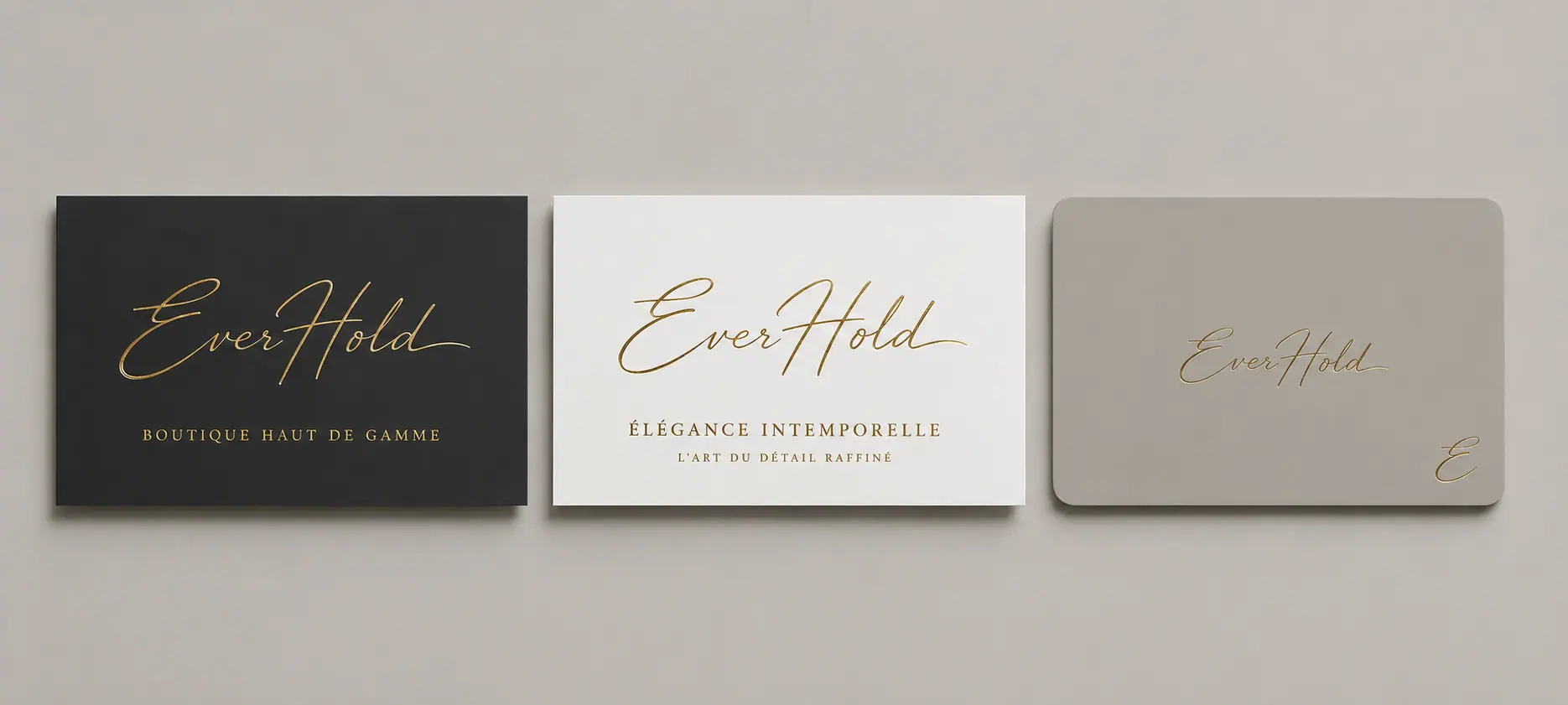 Trois cartes de visite luxueuses pour la marque EverHold alignées côte à côte. La première à gauche est noire avec le logo EverHold en dorure à chaud et le sous-titre "BOUTIQUE HAUT DE GAMME". Celle du milieu est blanche avec le logo doré et les mentions "ÉLÉGANCE INTEMPORELLE" et "L'ART DU DÉTAIL RAFFINÉ". La troisième à droite est taupe aux coins arrondis avec le logo et un monogramme "E" gravé en doré.